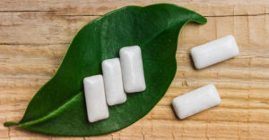 Four white pills on a green leaf provide 4 Ways to Maintain Your Oral Hygiene on the Go.